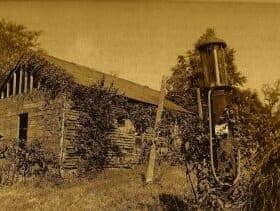 A rustic, vine-covered log cabin beside a vintage lantern.