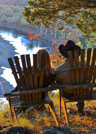man and lady sitting in chairs viewing river below