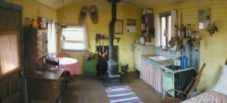 Line Camp Cabin interior with bed, antique stove, pot-belly stove fireplace and other furniture